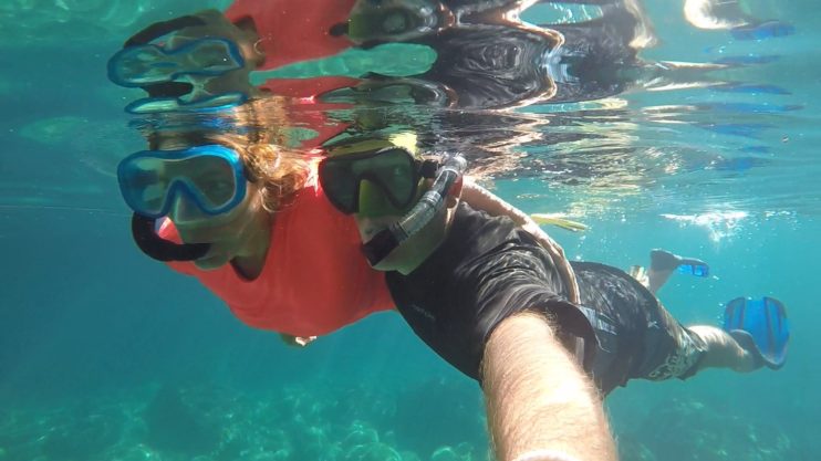 Two people snorkelling under water side by side